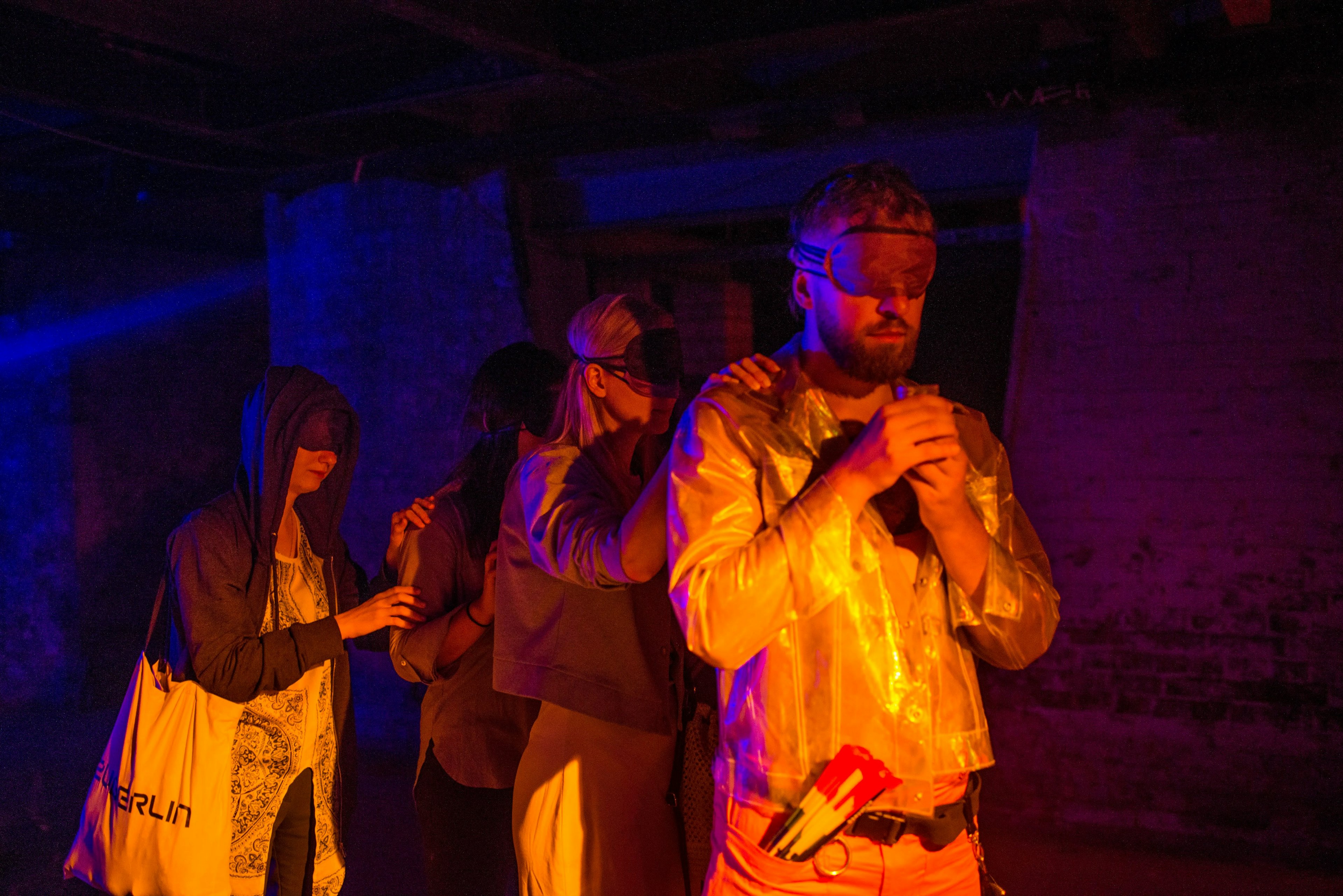 A blindfolded group of people in colorful light