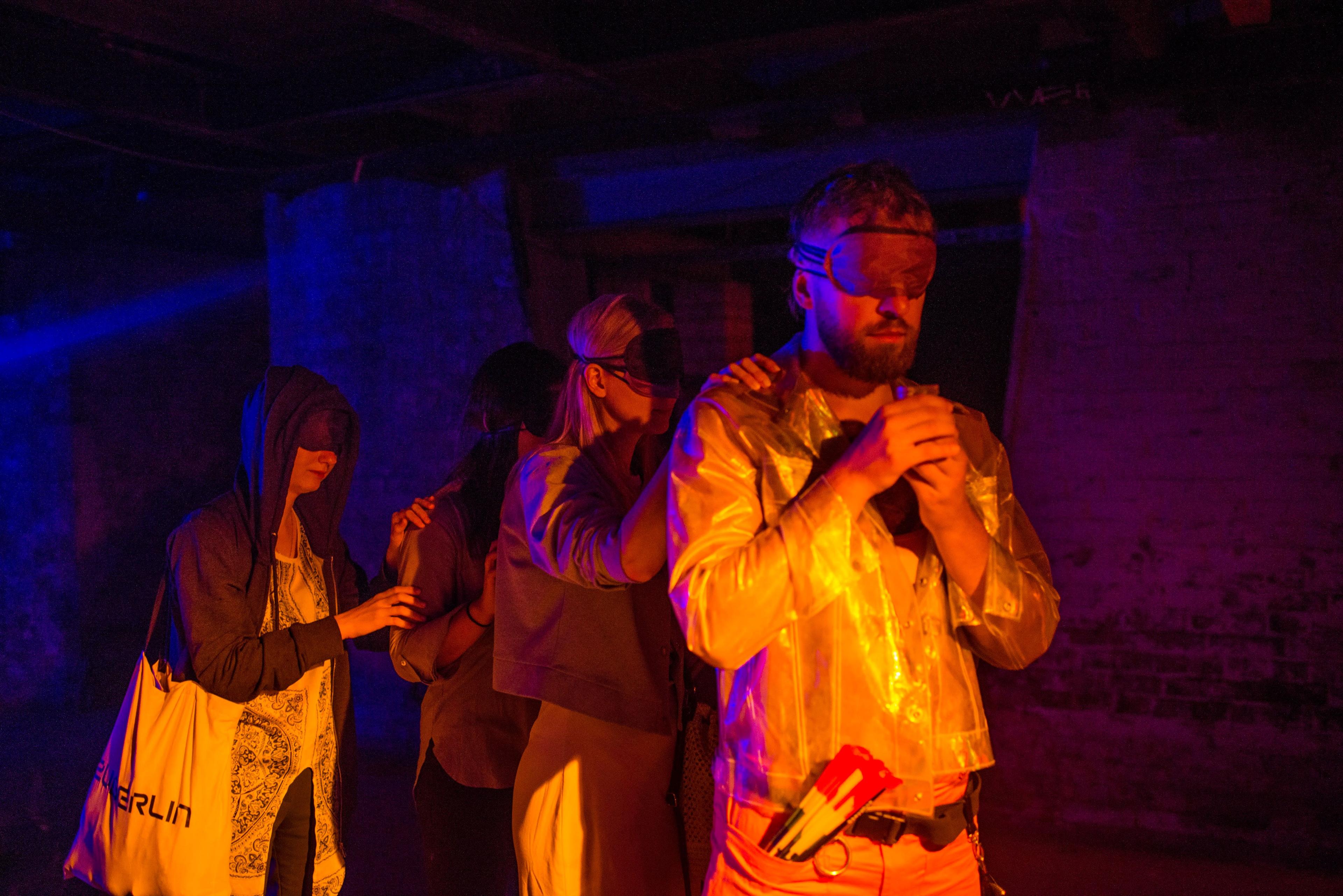 A blindfolded group of people in colorful light